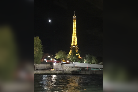 Night view of Eiffel Tower across water.