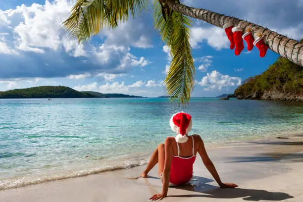 woman under a palm tree with Christmas stockings on a tropical beach, St. John, united states virgin islands